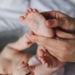 mains massant le pied d'un bébé