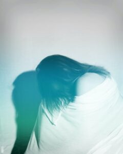image en noir et blanc. femme repliée sur elle, visage caché.